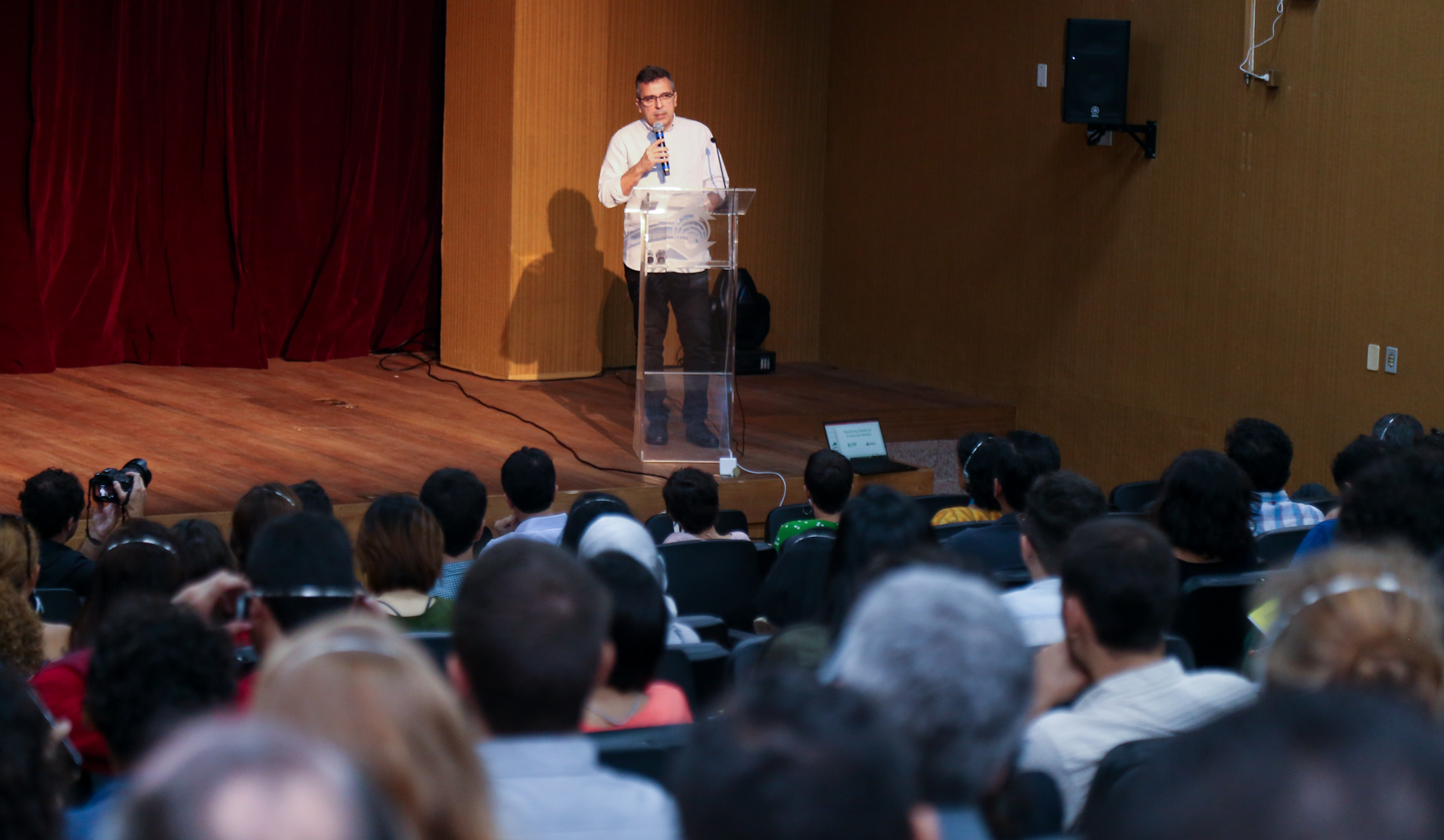 uma pessoa fala num palco para uma plateia
